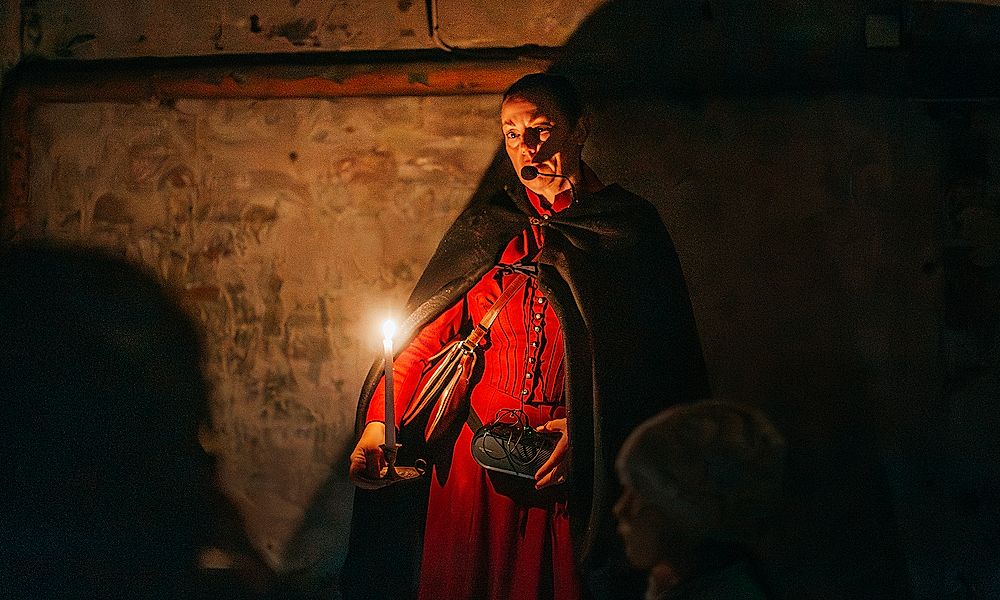 Guide med levande ljus berättar under spökvandring på Vaxholms kastell.